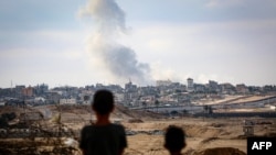 Архіўнае ілюстрацыйнае фота. Хлопчыкі назіраюць за клюбамі дыму падчас ізраільскіх удараў на ўсход ад Рафаха на поўдні сэктара Газа. 13 траўня 2024 году