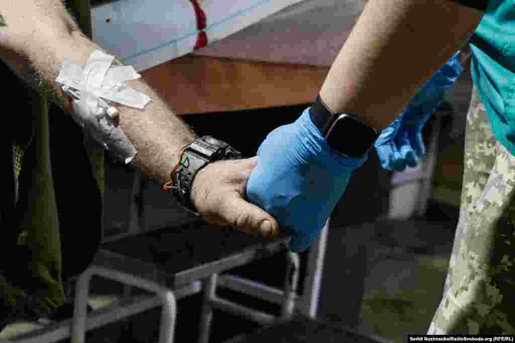Медик тримає за руку пораненого бійця. Бахмутський стабпункт, листопад 2022 року&nbsp;