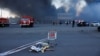 Тело погибшего на фоне горящего гипермаркета "Эпицентр" в Харькове после росийского удара двумя авиабомбами