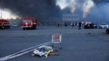 Тело погибшего на фоне горящего гипермаркета "Эпицентр" в Харькове после росийского удара двумя авиабомбами