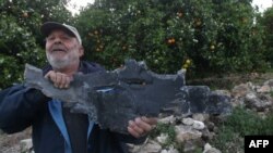 Muškarac pokazuje ostatak granate nakon izraelskih zračnih napada u Al Qulaylahu, predgrađe grada Tira, južno od libanonske prijestolnice Beiruta, 7. travnja 2023.
