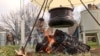 Zenica, Bosnia -- A pot brewing on a field during a traditional festival with an old man sitting in the background