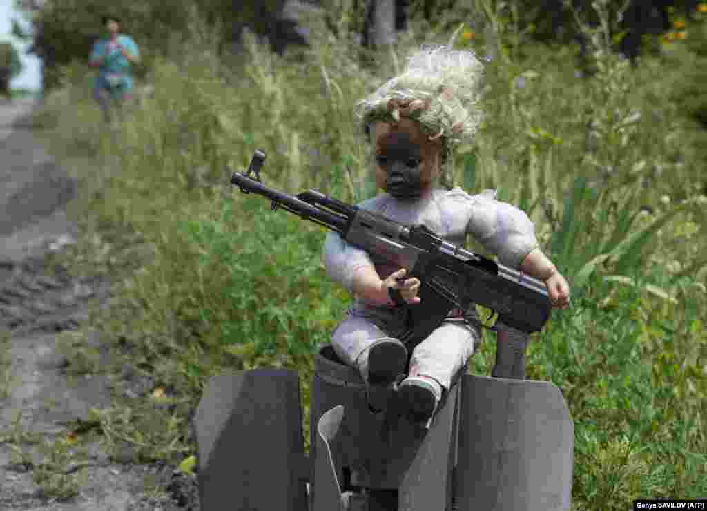 A doll holding a replica of an AK-47 assault rifle is set on the tailpiece of a rocket on a roadside near the town of Avdiyivka, Donetsk region, Ukraine.