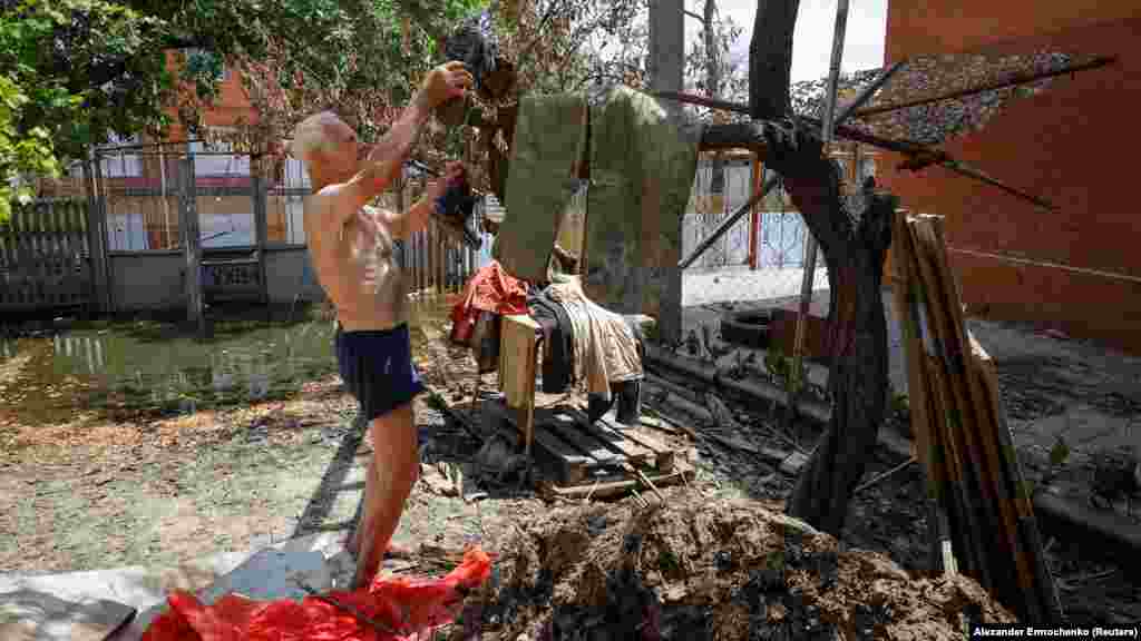 A nyolcvankét éves Valentin Garul egy faágon szárítja ruháit, miután a kahovkai gát összeomlását követő árvíz visszahúzódott Hola Prisztan településen. A kép 2023. július 6-án készült