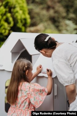 Юля Родіна разом із донечкою Єсенією розмальовує іграшковий будинок.