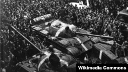 Громадяни Чехословаччини зупиняють радянські танки Т-55, позначені так званими «смугами вторгнення», під час окупації країни військами Варшавського договору (операція «Дунай»). 1968 рік