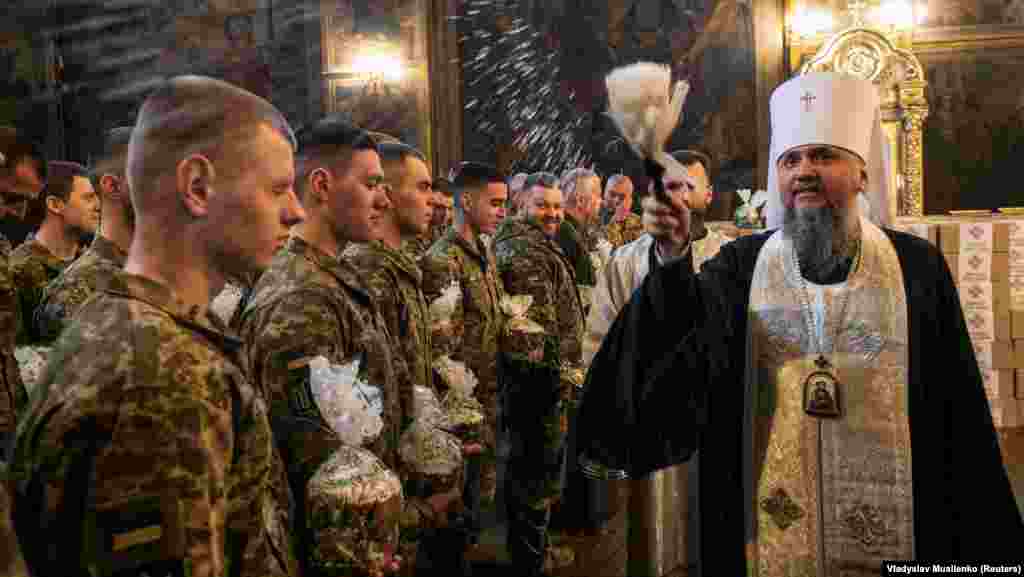An Orthodox priest sprinkles holy water on Ukrainian soldiers holding paschas during a special service for the Ukrainian Armed Forces ahead of Easter at St. Michael&#39;s Cathedral in Kyiv.