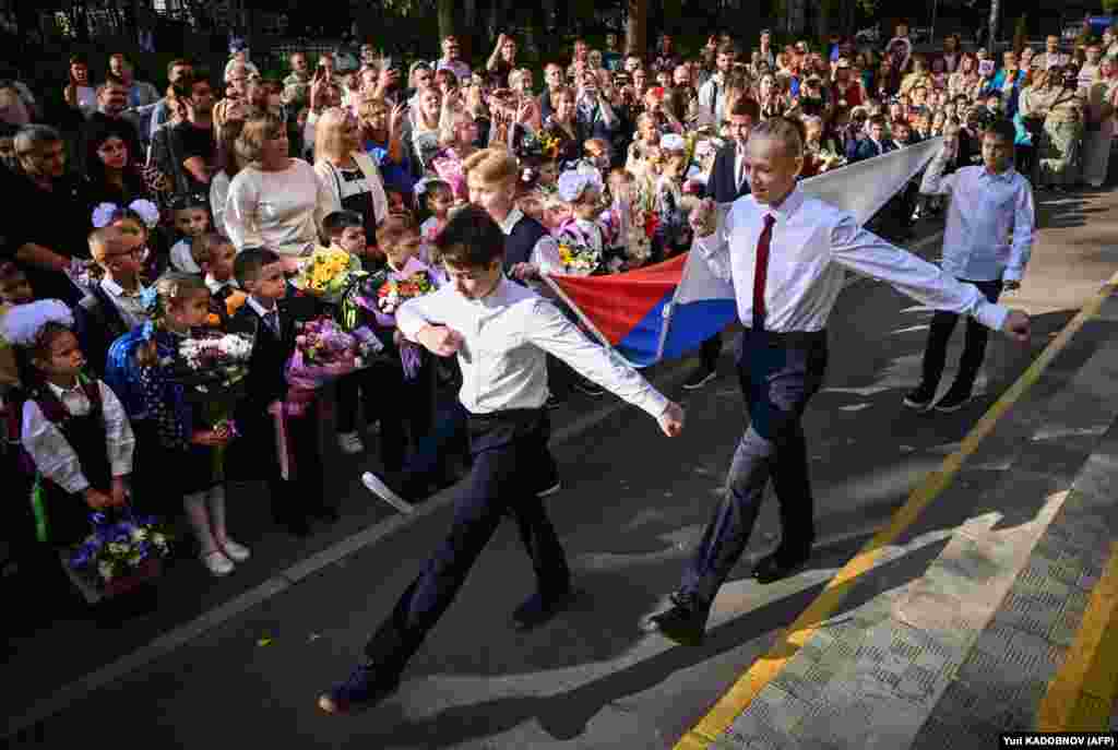 Russian schoolboys parade with a Russian national tricolor flag during a &quot;first bell&quot; ceremony in Moscow on September 1.&nbsp;