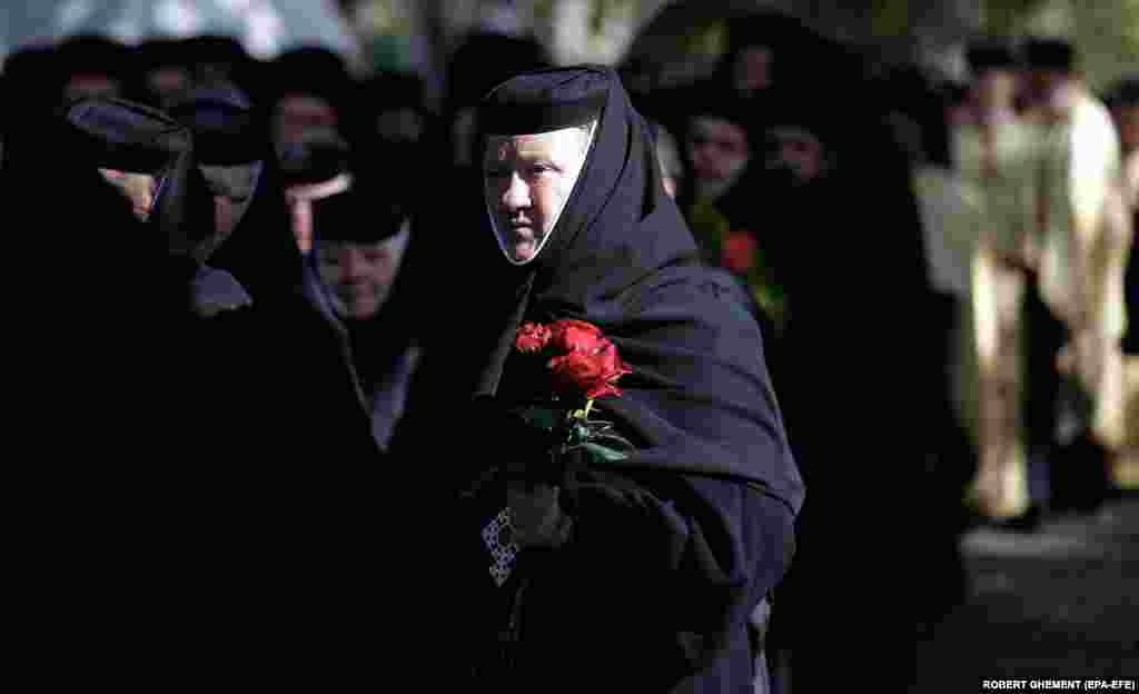 Një murgeshë ortodokse rumune mban trëndafila të kuq gjatë një procesioni pranë Katedrales Patriarkale në Bukuresht.