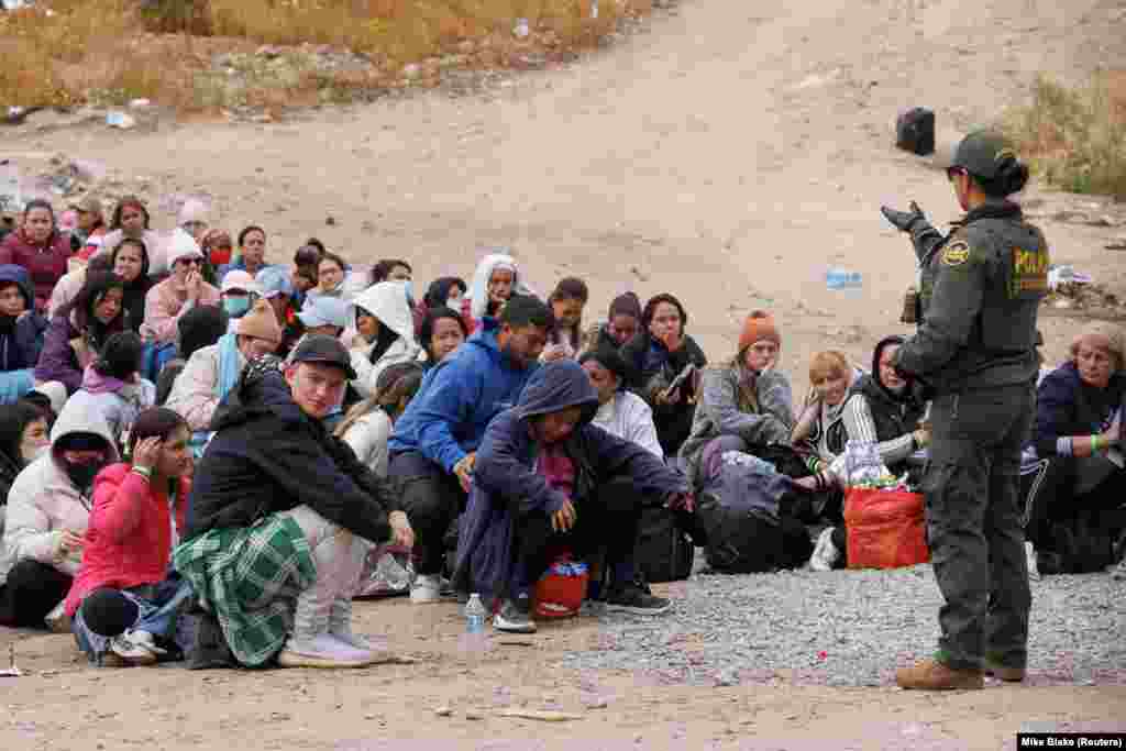 Një oficere e Patrullës Kufitare të SHBA-së duke iu folur emigrantëve të grumbulluar në një zonë mes gardheve parësore dhe dytësore kufitare, në kufirin me Meksikën, afër San Diegos, më 10 maj 2023.