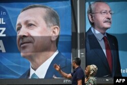 Пара проходит мимо рекламных щитов с портретами президента Турции Реджепа Тайипа Эрдогана (слева) и лидера Народно-республиканской партии (НРП) и кандидата в президенты Кемаля Кылычдароглу (справа) в Шанлыурфе, юго-восток Турции, 28 апреля 2023 года