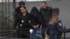 Cu capul acoperit, adolescentul care a ucis opt elevi este escortat de poliție în fața școlii primare Vladislav Ribnikar din Belgrad, pe 3 mai.