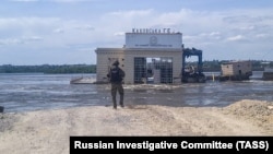  Служител на Следствения комитет на Русия пред Каховската водноелектрическа централа в Нова Каховка след разрушаването на язовирната стена 