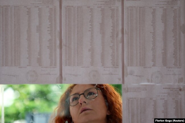 Një qytetare në Tiranë duke shikuar listat e votuesve të vendosura para një qendre të votimit në Tiranë.