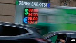 Elektronska tabla sa kursevima u menjačnici se vidi kroz saobraćaj u Moskvi, Rusija, četvrtak, 13. juna 2024.