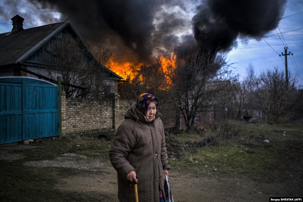 Një grua e moshuar qëndron pranë një ndërtese të djegur pas granatimeve në Kostyantynivka, rajoni Donetsk.
