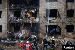 Пожарные работают у поврежденного жилого дома в Киеве 2 января 2024 года