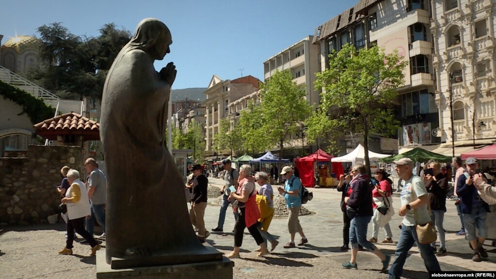 Turistët shijojnë rrezet e diellit në Shkup pranë një prej 280 statujave të tij të vendosura gjithandej nëpër kryeqytetin maqedonas.