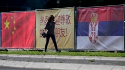 Žena prolazi pored kineske i srpske zastave u Beogradu 7. maja 2024. godine, uoči posete kineskog predsednika Srbiji.