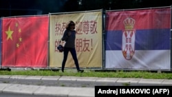 Žena prolazi pored kineske i srpske zastave u Beogradu 7. maja 2024. godine, uoči posete kineskog predsednika Srbiji.