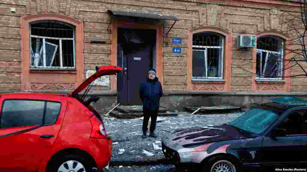 Човек стои во близина на оштетени возила. По пауза од 44 дена, непријателот изврши нов ракетен напад врз Киев, рече Попко. &bdquo;Сите служби за итни случаи работат на лице место. Последиците од ракетниот напад се елиминираат&ldquo;, додаде тој.