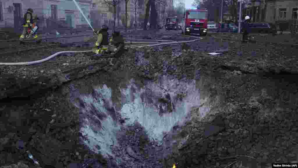 Пожарникарите работат во близина на кратерот на бомба по рускиот напад во Киев. Првичните извештаи велат дека најмалку три области во главниот град претрпеле штета, вклучително и станбени области и трафостаница.