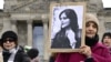Акція 8 березня у Берліні – жінка тримає портрет Махси Аміні