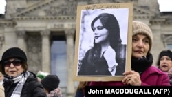 Акция 8 марта в Берлине - женщина держит портрет Махсы Амини