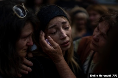 Në një funeral në Buça më 31 gusht 2022, Anastasia Ohrimenko, 26 vjeç, ngushëllohet nga të afërmit dhe miqtë teksa qan për humbjen e bashkëshortit të saj, Yuriy Styhlyuk, një ushtar ukrainas që u vra në luftime.