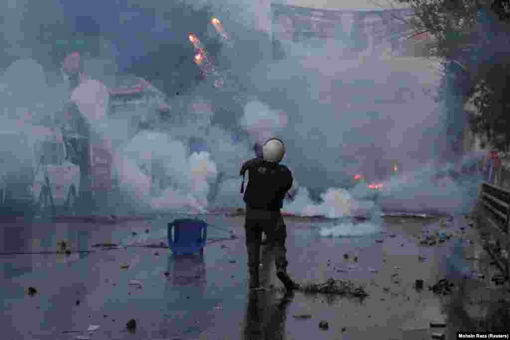 A police officer fires a tear gas shell to disperse Khan&#39;s supporters.