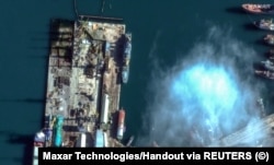На спутниковом снимке виден российский военный корабль в порту Феодосия. Внизу слева возле причала находится балкер SAN COSMAS. 5 декабря 2023 года. Maxar Technologies/REUTERS