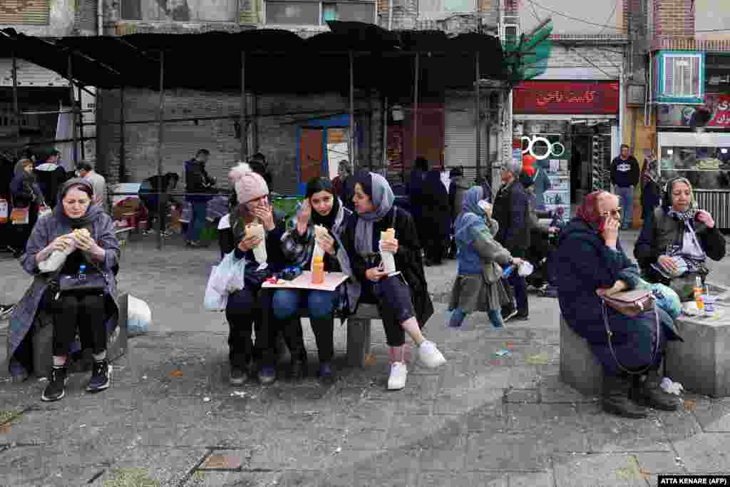 Iranian women eat as they sit in a commercial area in Tehran.&nbsp;