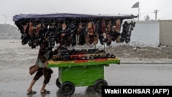 An Afghan vendor pushes a cart of footwear through a street as it rains in Kabul on May 23. 
