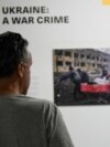 Një grua shikon një nga fotografitë e ekspozitës "Ukraina: Një krim lufte", që u hap në Prishtinë më 29 prill 2024. 