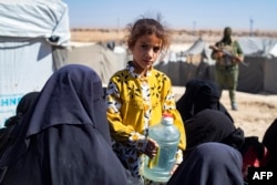 Djevojčica u kampu Al-Hol drži kanister za vodu tokom inspekcije šatora njene porodice, Sirija, 28. avgust 2022.