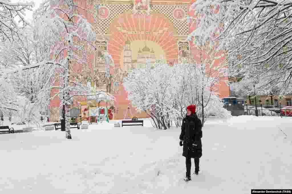 A woman walks by a mural on a building facade during a snowfall in St. Petersburg on March 29.