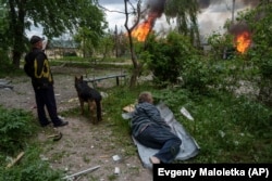 Чоловік лежить на землі, дивлячись на свій палаючий будинок, зруйнований російською авіацією, Вовчанськ, 11 травня 2024 року