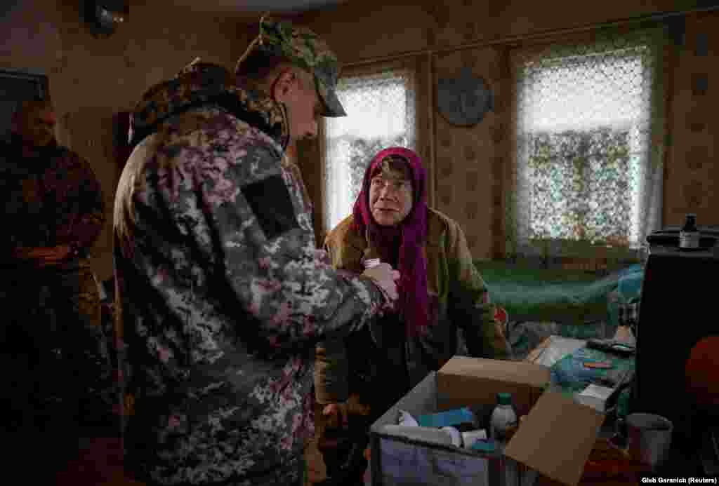 Jevdokija Beznoscsenko, aki harminchét évvel ezelőtt úgy döntött, hogy itt marad, a 2022 óta tartó háború óta ki van szolgáltatva az ukrán hadsereg segélyszállítmányainak. A képen gyógyszert kap egy katonától 2023. október 18-án