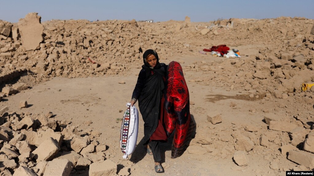 Una donna afghana trasporta un materasso e un cuscino che ha recuperato dalla sua casa distrutta.