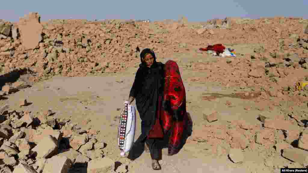 &nbsp;An Afghan woman carries a mattress and pillow that she salvaged from her destroyed home.