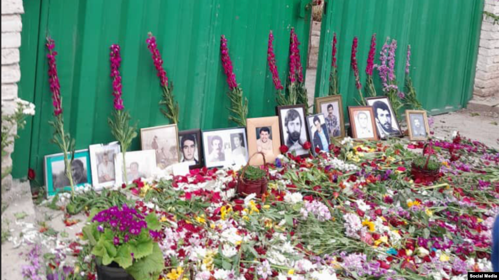 ورودی آرامستان خاوران جایی که عکس شماری از قربانیان اعدام‌های دهه ۶۰ و دسته‌های گل قرار داده شده است.