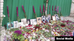 ورودی آرامستان خاوران جایی که عکس شماری از قربانیان اعدام‌های دهه ۶۰ و دسته‌های گل قرار داده شده است.