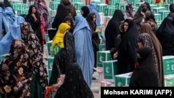 Afghan women gather around aid parcels that they received from the King Salman Humanitarian Aid and Relief Center in Herat in June.