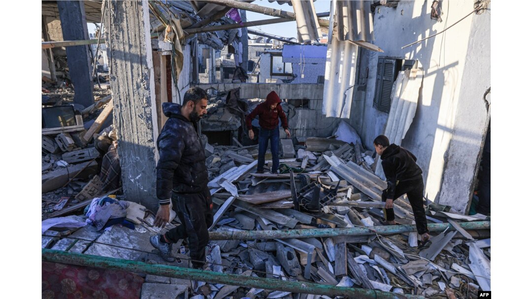 Palestinieni caută printre dărâmăturile unei clădiri în urma unui bombardament israelian la Rafah, în sudul Fâșiei Gaza, pe 26 decembrie 2023.