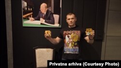 Vlado Stanić ispred fotografije predsednika Rusije Vladimira Putina. Stanić je fotografiju ustupio RSE na korišćenje. Vreme i mesto nastanka fotografije nisu poznati redakciji.
