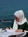 A woman reading a book by the sea in Deir al-Balah in Gaza