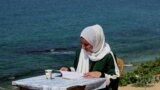 A woman reading a book by the sea in Deir al-Balah in Gaza