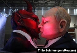 Фігури, які зображають президента Росії Володимира Путіна і диявола, виготовлені для щорічного карнавалу в німецькому місті Майнці, 14 лютого 2023 року