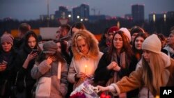 Az emberek virágot helyeznek el és gyertyát gyújtanak a péntek esti támadás helyszínén, Moszkva nyugati szélén 2024. március 23-án