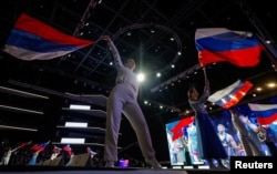 Учасники церемонії розмахують державними прапорами Росії під час офіційного відкриття чемпіонату Росії з вільної боротьби (етапу підготовки до Олімпійських ігор) у комплексі Live Arena поблизу Москви, 4 травня 2024 року